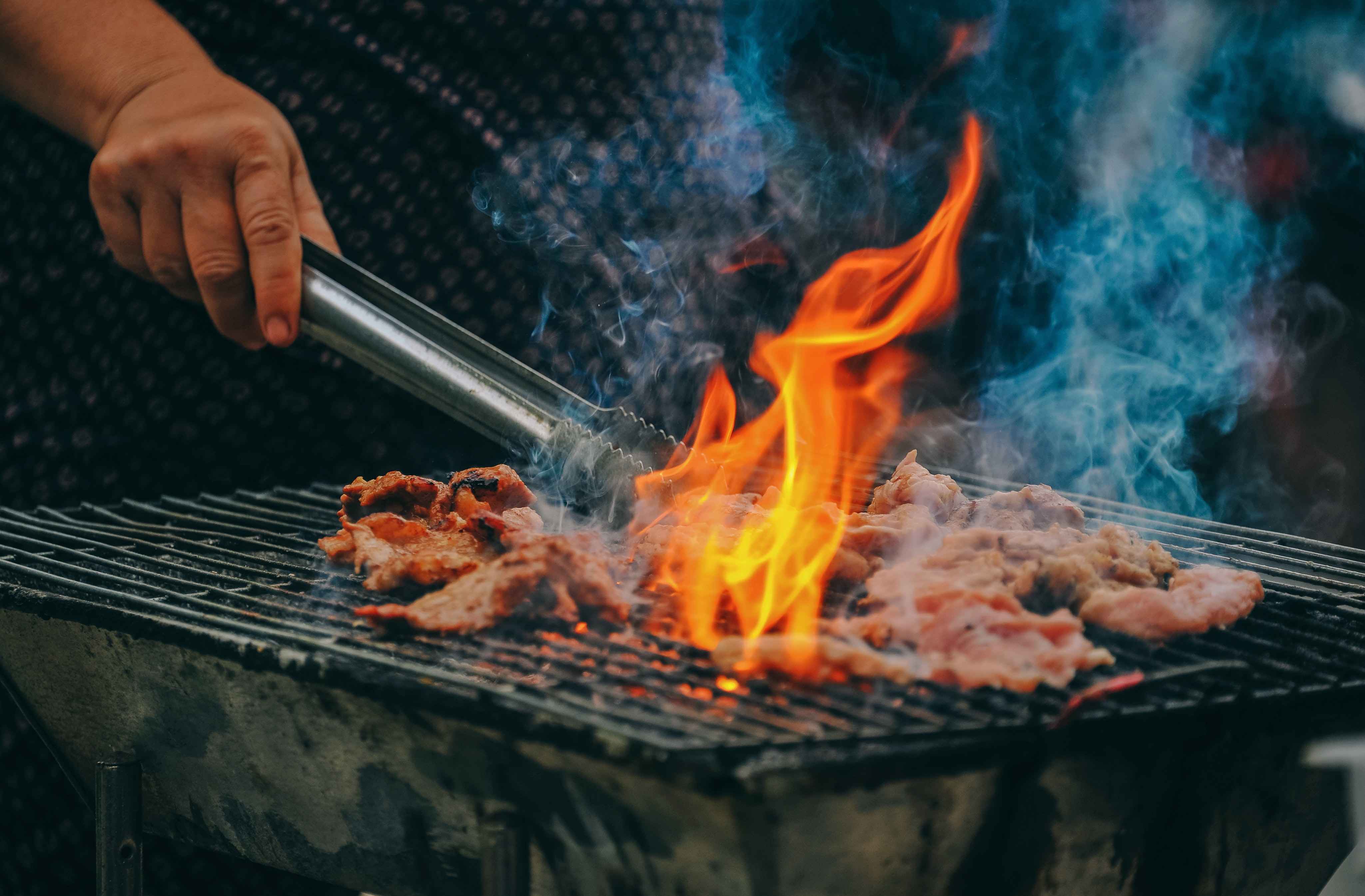 Cooking meat over a flaming grill