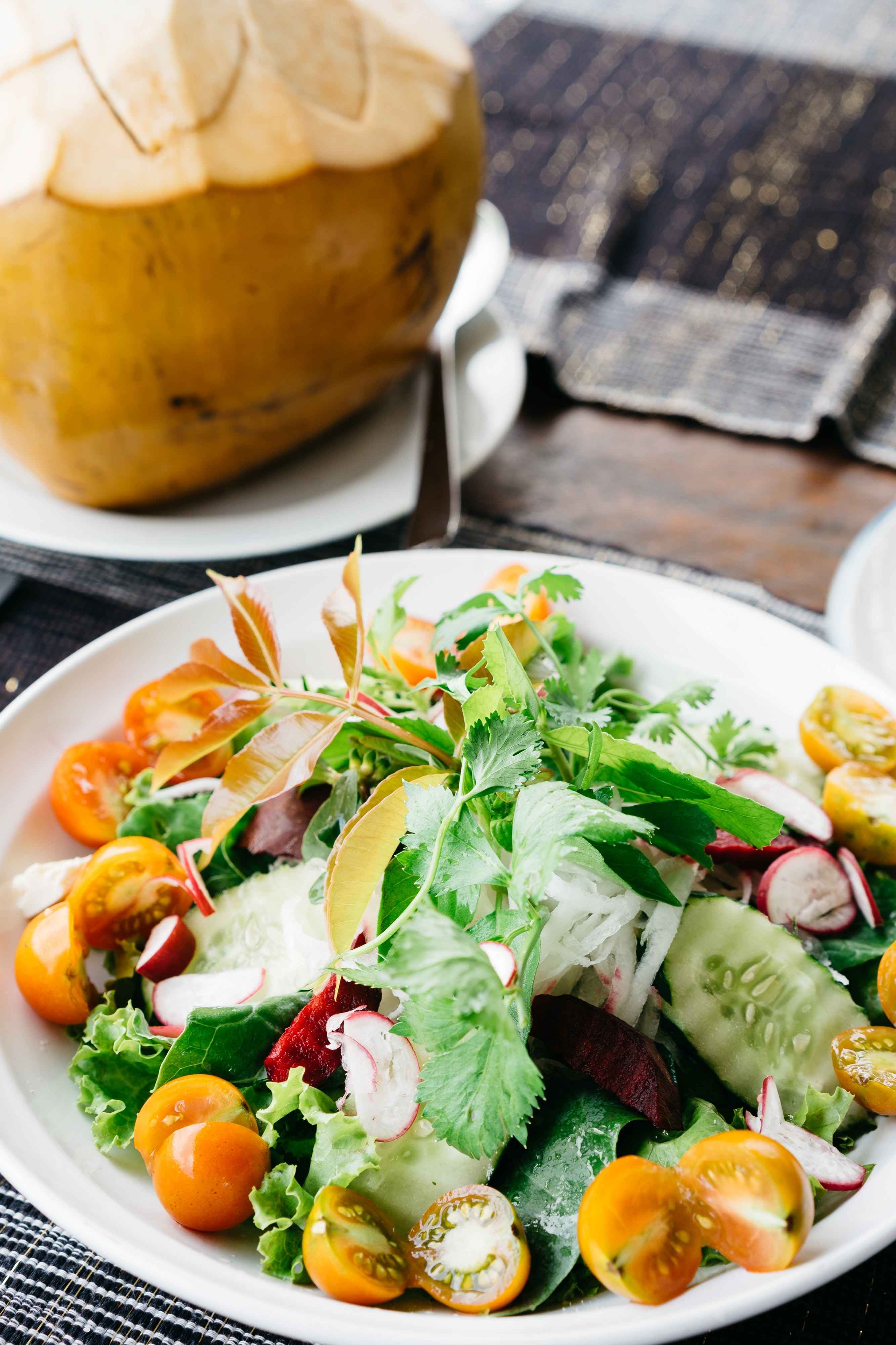 A bowl of salad and fresh coconut on a table